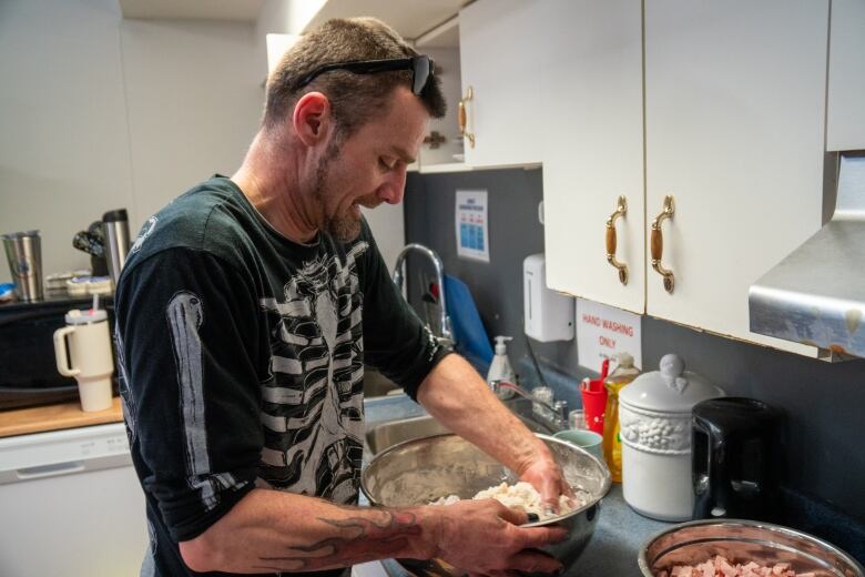 A person kneads dough in a kitchen.