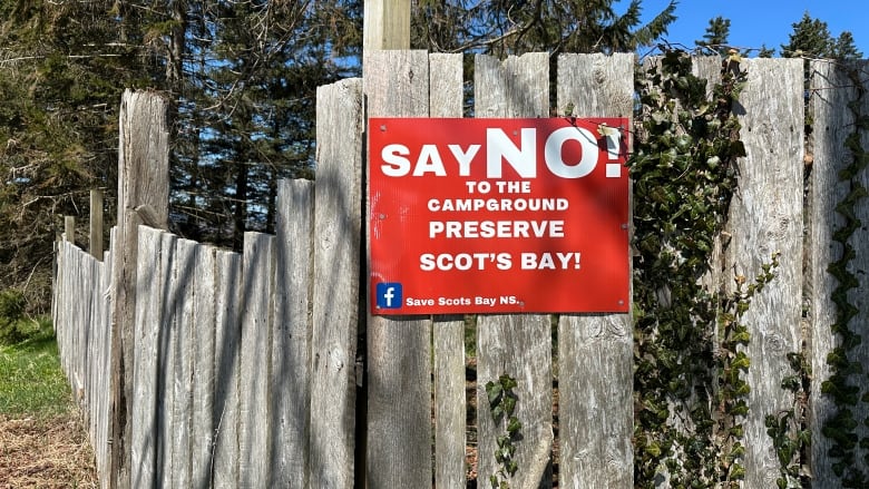 A red sign on a fence reads 