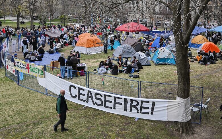 Fence erected around an encampment where pro-Palestinians protesters have gathered on a field at McGill University. Banners hang from the metal fence including one that reads: ceasefire.