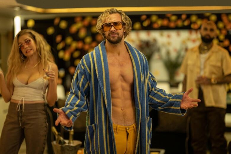 A man in a robe shows off his well toned stomach, the man is actor Aaron Taylor-Johnson who plays an egocentric actor, Tom. 