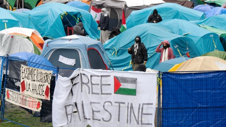 Tents are surrounded by fencing with banners that say Free Palestine.