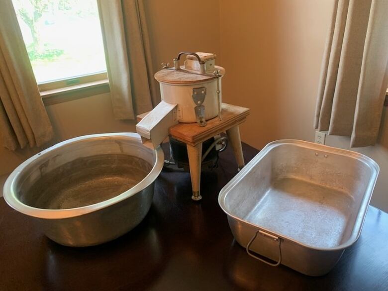 Two metal basins are shown alongside a device that used to grate potatoes.