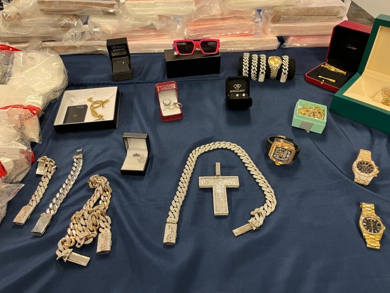 Cash, guns, drugs, and jewelry are on display on a table