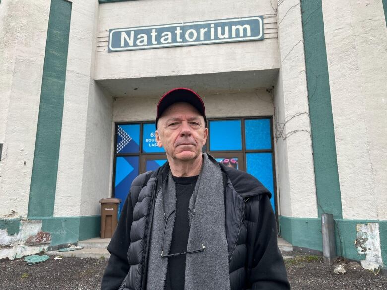 A man stands in front of a building.