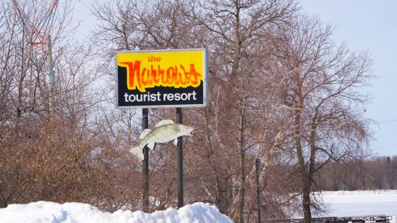 A sign reads 'Narrows Sunset Resort' overtop a sign depicting a walleye, a kind of fish found in Canada.