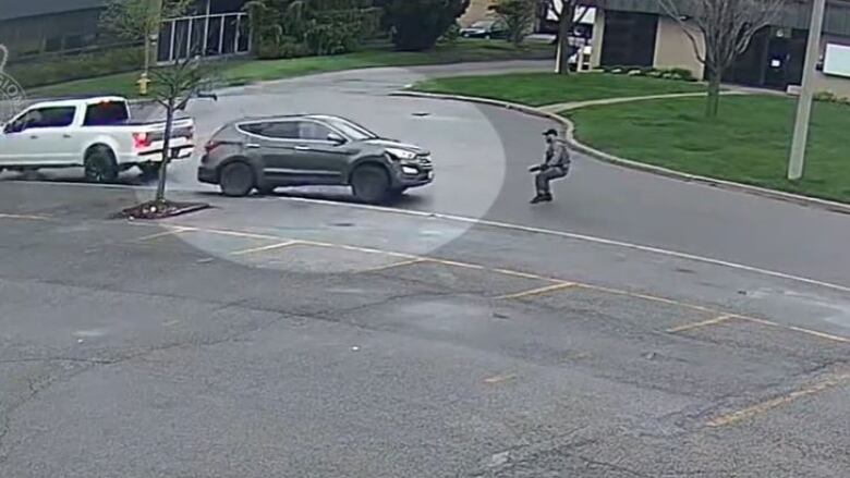 A security camera screenshot of a car heading towards a person.