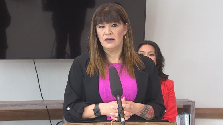 A woman is pictured speaking at a podium.