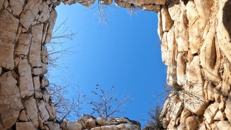 A look up to a blue sky from within a limestone structure.