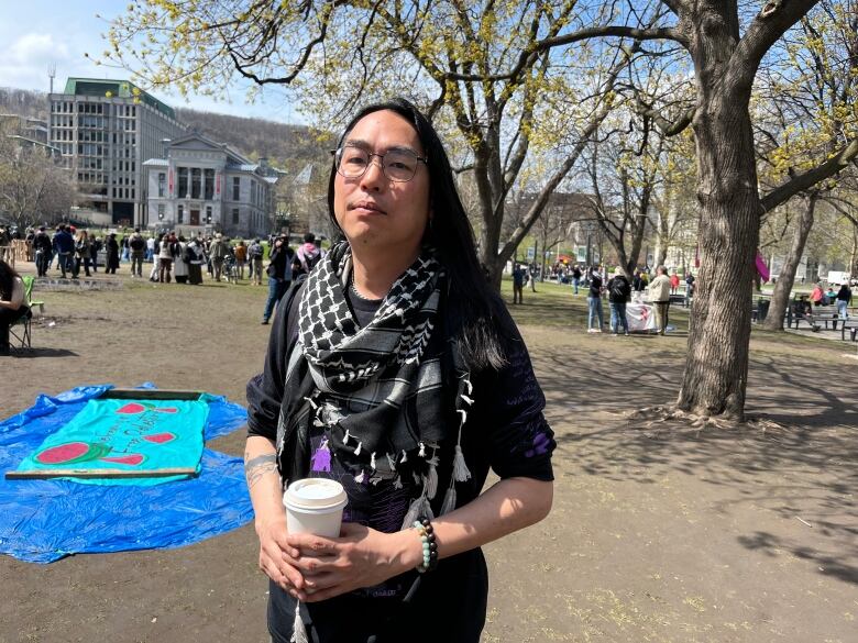 a man wearing a keffiyeh and holding a coffee