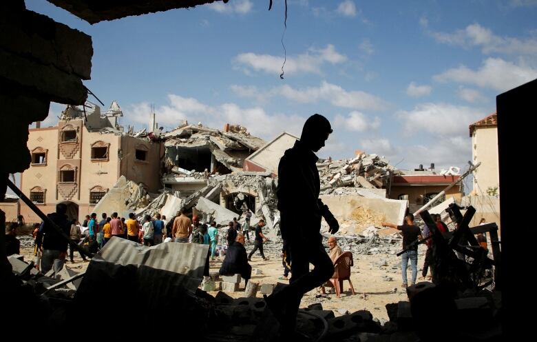 People inspect the rubble of destroyed buildings.