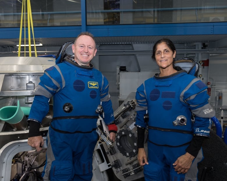 A man and woman are in blue space suits.