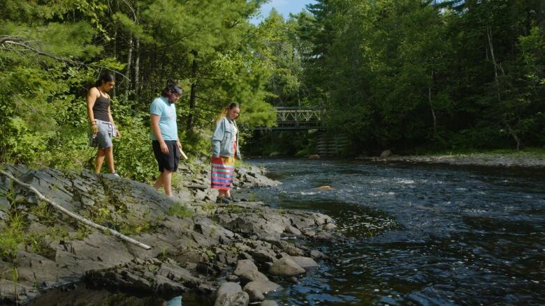 three people walking alongside a lake