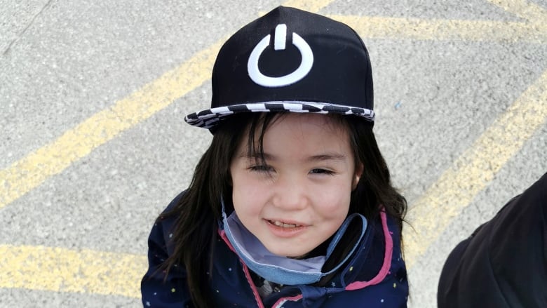 A girl with dark hair wearing a black hat.