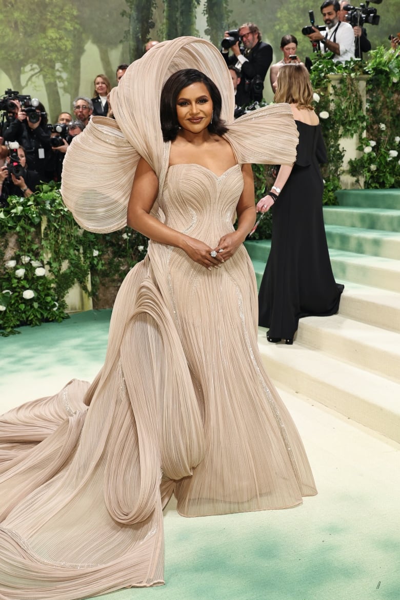 Mindy Kaling on the red carpet for the 2024 Met Gala wearing a beige, sculptural dress.