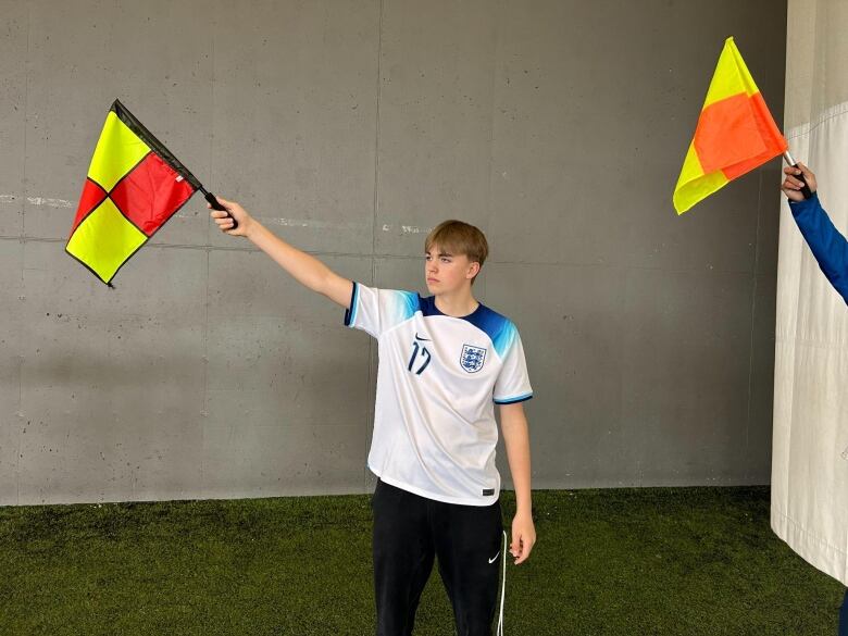 A young man holds a flag in his right hand.