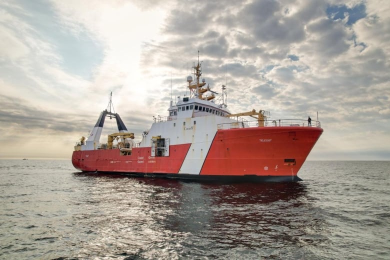 A large red and white ship in the Atlantic Ocean under a cloudy sky.