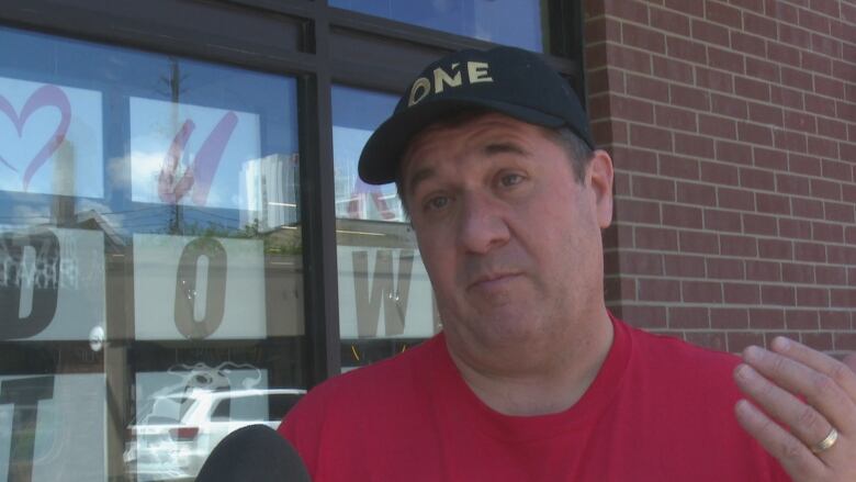 A man wearing a red T-shirt in a downtown area.