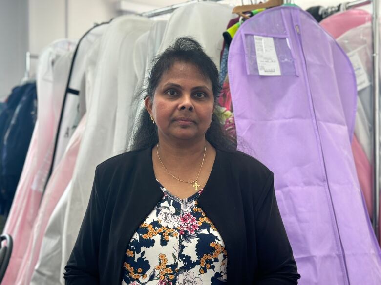 Seamstress in front of a bunch of poofy dresses.