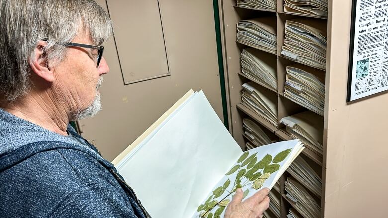 A scientist flips a folio of plant clippings at his home.