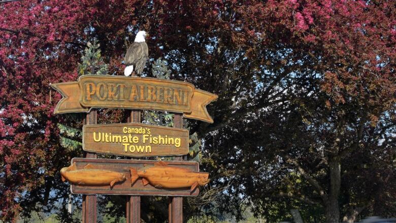 A stylishly carved wooden sign topped by a sculpted wooden eagle has the words Port Alberni and underneath: Canada's Ultimate Fishing Town atop two sculpted wooden fishes.