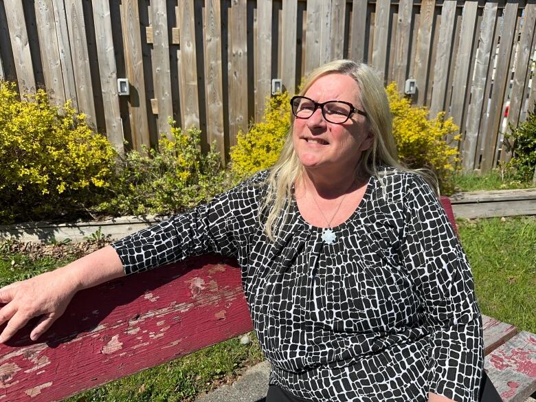 A woman is shown sitting on a bench at a park in Shelburne where the tribute will be placed on the fence behind her.