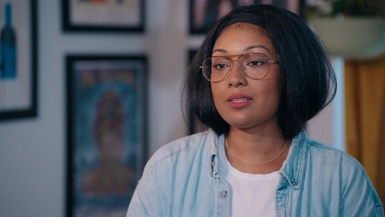 A woman with black hair, metal glasses and wearing a denim shirt.