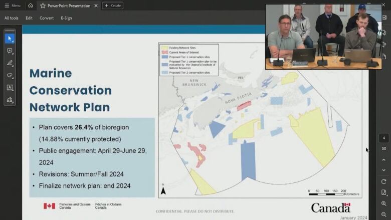 a map is shown on a computer screen. Presenters appear in the top right, sitting at a table. 