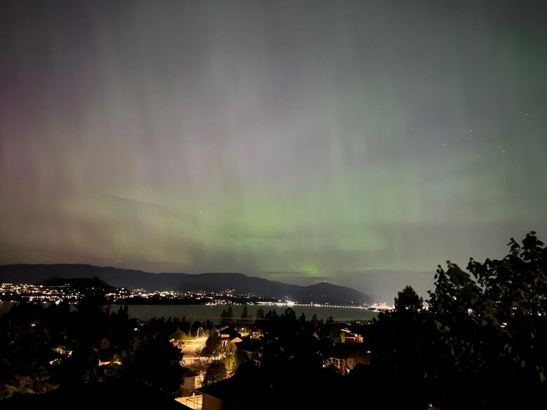 Northern lights above a lakefront city.