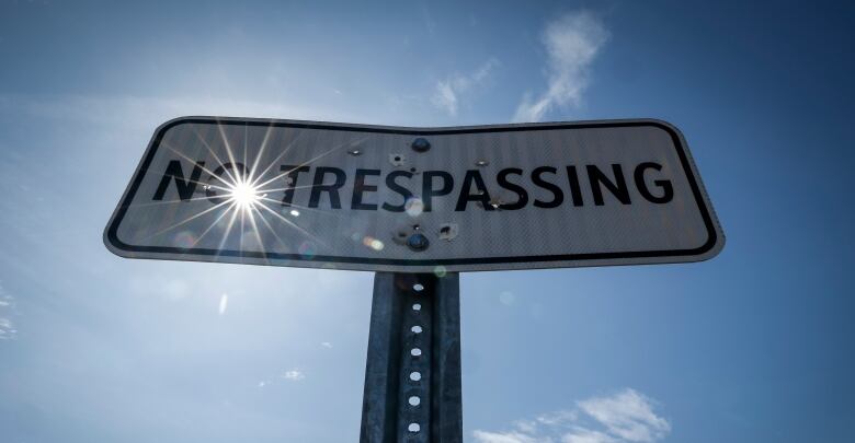 A No Trespassing sign with bullet holes in it.