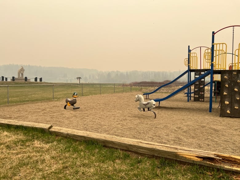 A playground with slides and cartoon animals is blanketed by smoke.