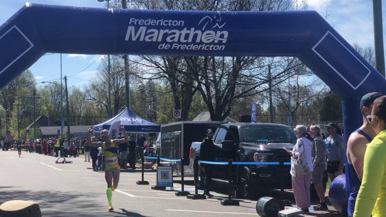 A runner waves and smiles as she crosses the finish line.