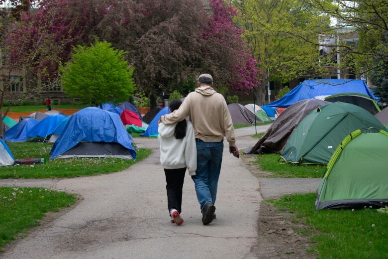 A man and child walking near tents.