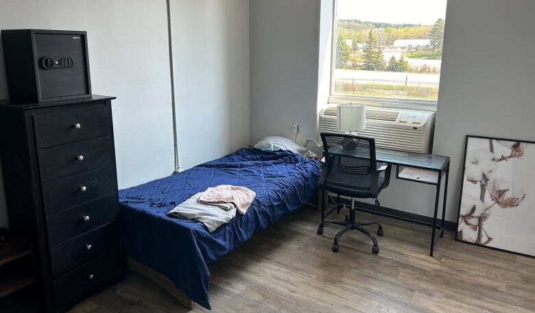 a simple bedroom with a bed, dresser and window