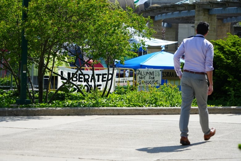 A man walks by an encampment with a sign that says 'Liberated Zone'