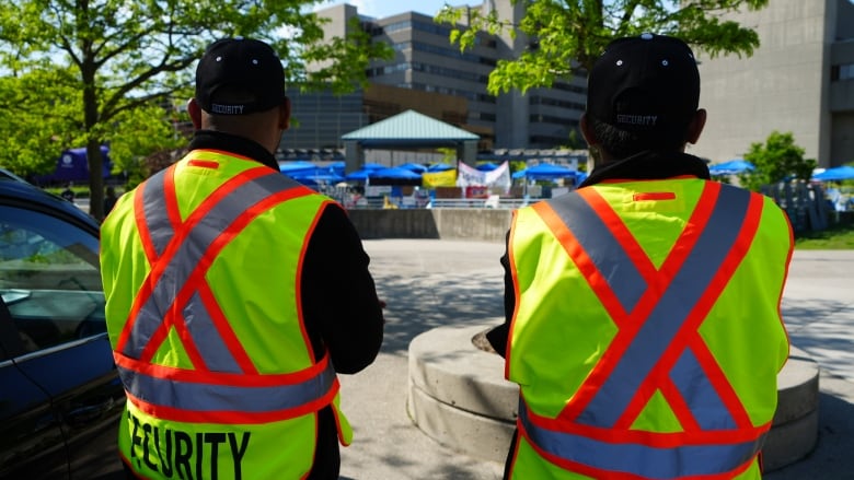 Two security guards watch a protest at Western University in London, Ont.