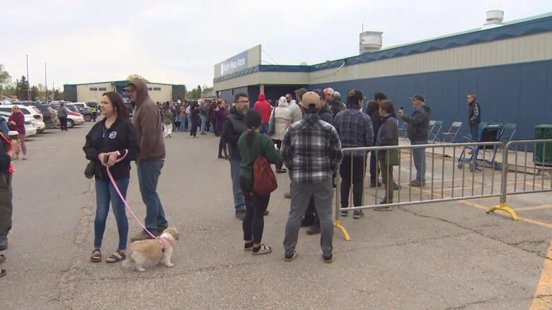 A long line of people outside in a parking lot