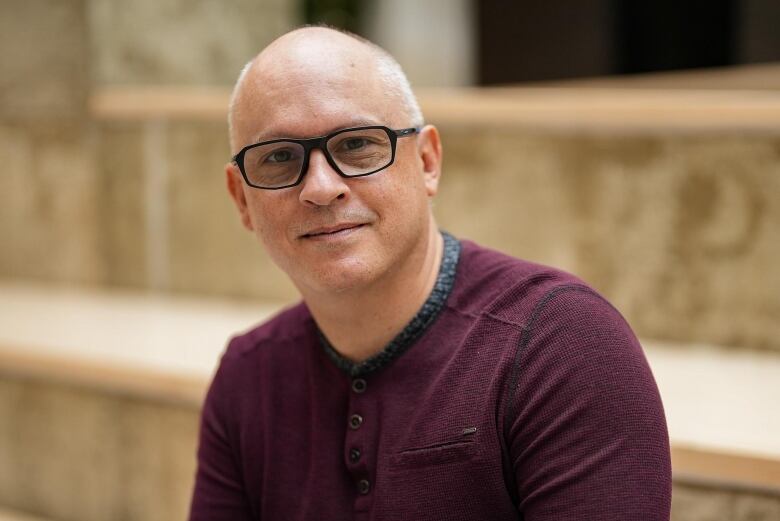 A photo of a man wearing glasses and a maroon shirt 