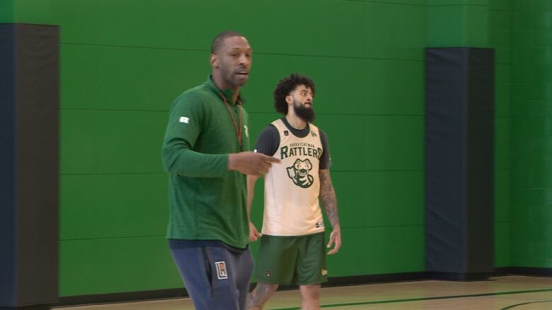 A basketball coach and player in a gym.