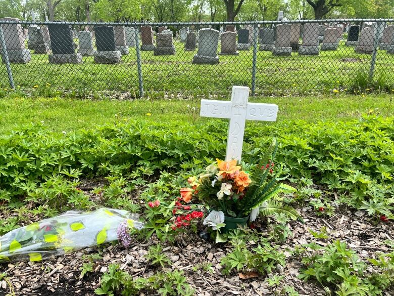 flowers on grass next to a cross 