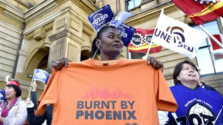 A member of Union Local 70130 holds a shirt during a protest against the Phoenix pay system outside the Office of the Prime Minister and Privy Council in Ottawa on Thursday, Oct. 12, 2017.