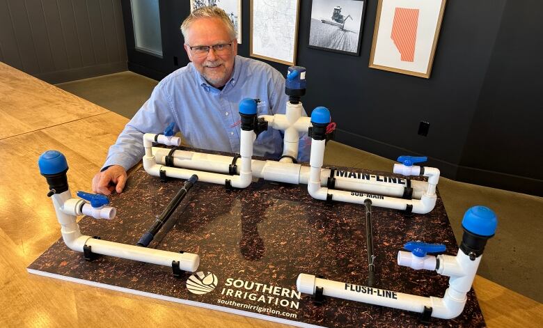 A man sits at a large table with a board that has pipes on it. 