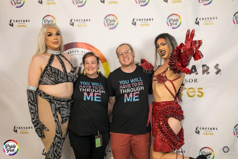 A couple pose with drag queens.