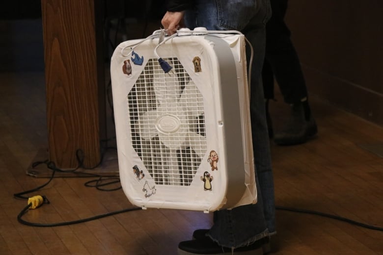 A handheld white device featuring a fan behind a grill.