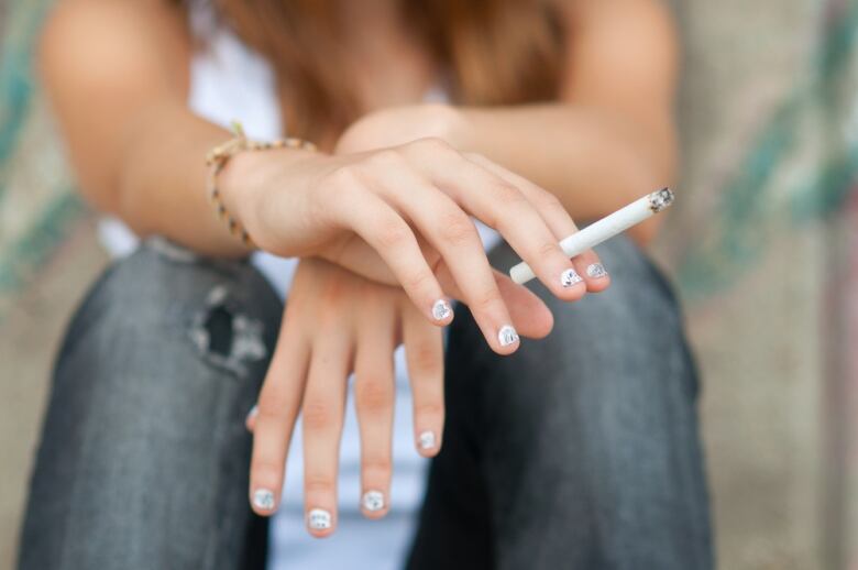 Woman holding cigarette.