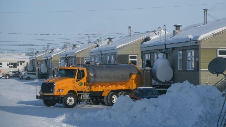 A truck in a small town. There is snow on the ground. 