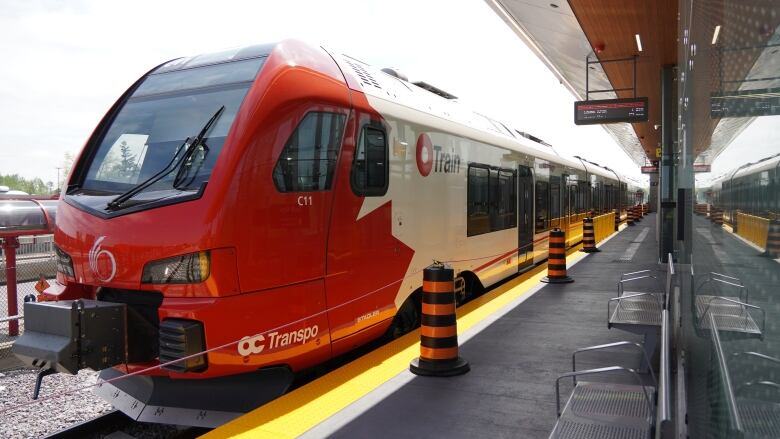 A red and white train stops at a closed train station