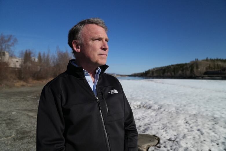 A man stands near an ice-covered lake.