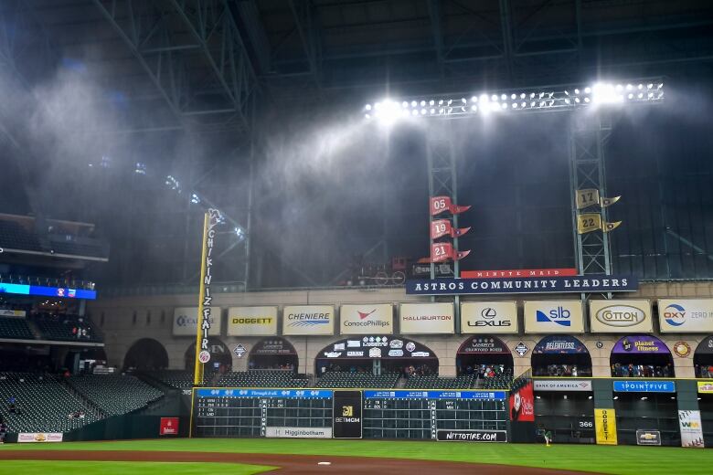 Rain is visible in the floodlights of a baseball stadium.