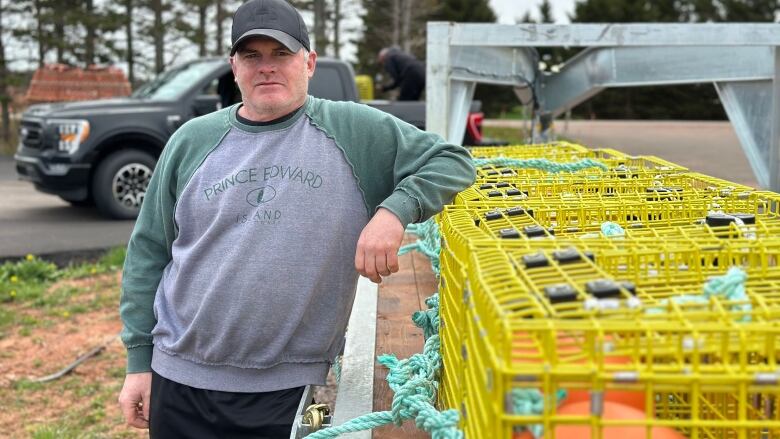 A man stands next to a snow crab trap.