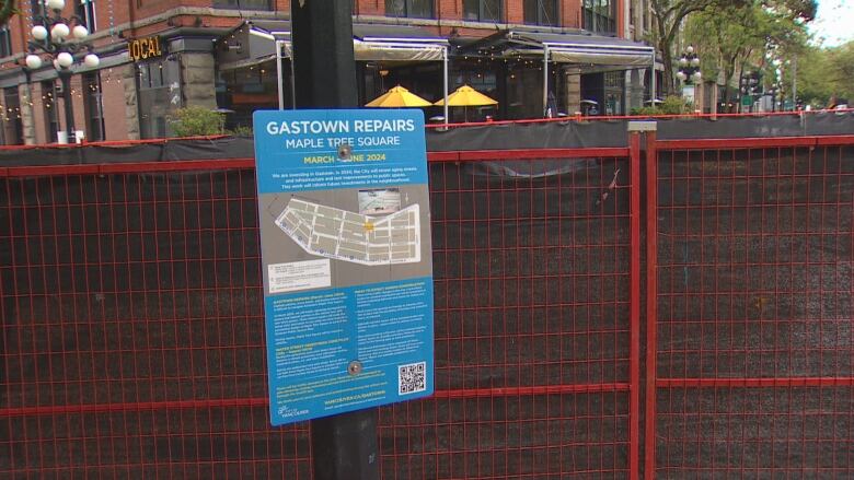 A fenced off area blocking a construction site with a sign that includes information about the project. 